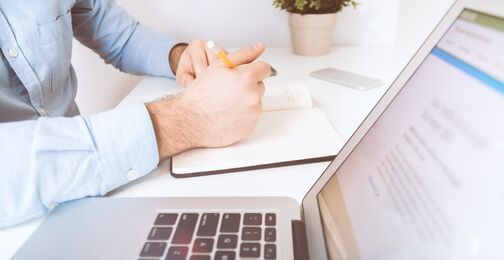 Mitarbeiter macht sich am Laptop Notizen