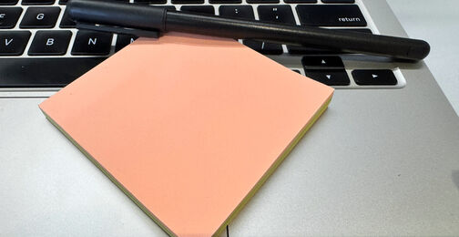 Stift und Notizzettel auf einer Laptop-Tastatur